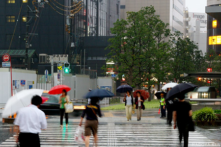 傘を差すひとが行き交う名古屋駅前